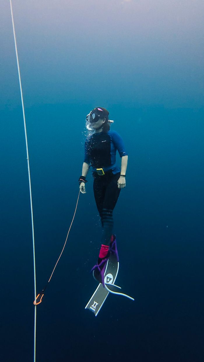 about-us-img A scuba diver descends into deep blue ocean depths near a guide rope.